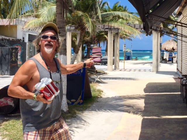 Theo at the doorway of our waterfront apartment rental in Mahahual, Mexico, in 2016, holding beer.