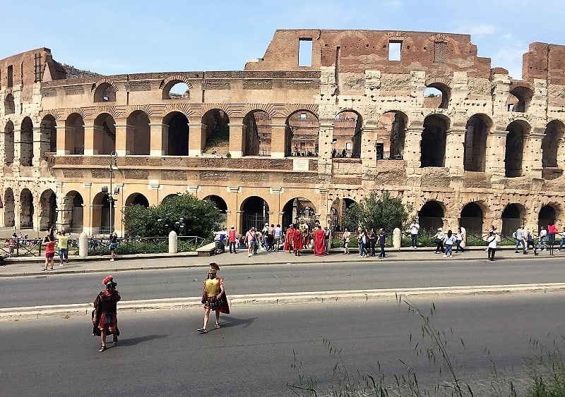 locals wear roman costumes outside the colosseum in rome
