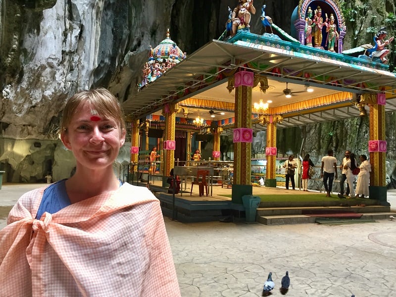 woman with powder on her forehead in front of a temple inside the batu caves