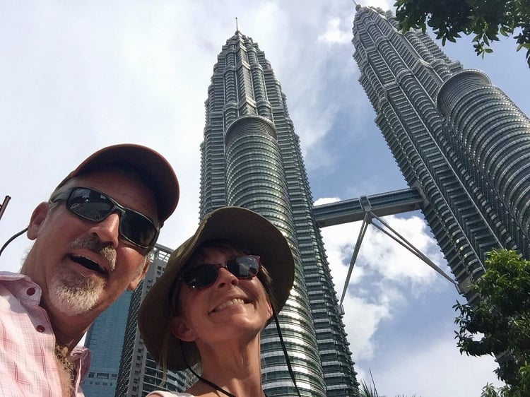 Two people in front of the iconic twin towers in Kuala Lumpur, Malaysia - how to retire early and travel the world