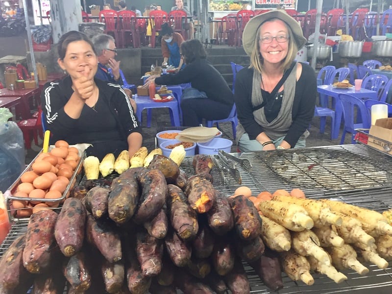 two women sit in front of smoked sweet potatoes at the dalat night market