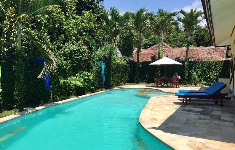 A beautiful pool with green trees around it as a man plans to travel the world in retirement.
