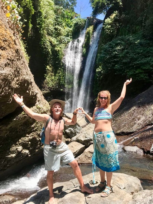 man and woman smile in front of the aling-aling waterfall after cliff jumps in bali