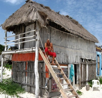 A man sits on the stairs to a beach hut in Tulum, Mexico