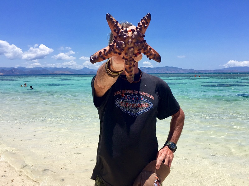 a man holds up a starfish big enough to cover his head