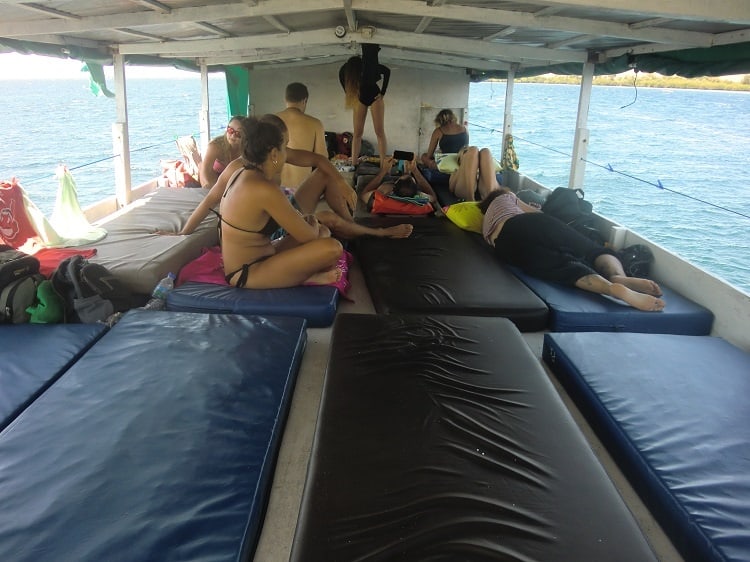 people sitting on mats in the sleeping area of a cheap komodo dragon boat tour