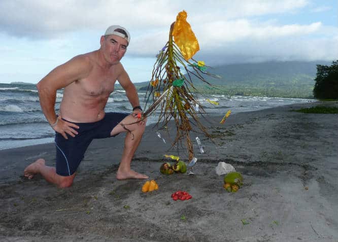 tedly kneels on the beach by his trashy christmas tree in nicaragua
