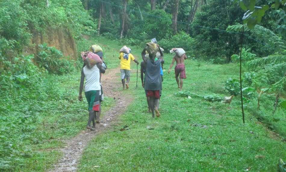 Ati men carry supplies up the mountain footpath to Kurong Village in June 2020.