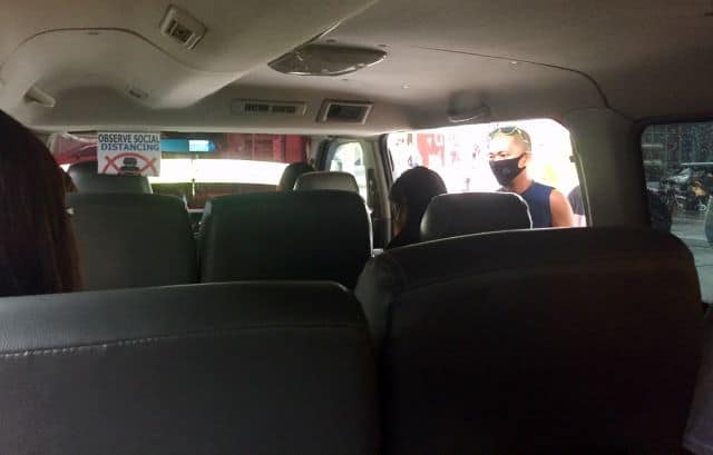 Inside a passenger van, or 'V-hire', in Aklan Province. It's half empty and a sign says, 'observe social distancing.'