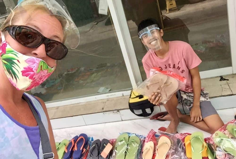 Ellen smiles under a mask with the flip-flop seller on a street corner, a thin young man.