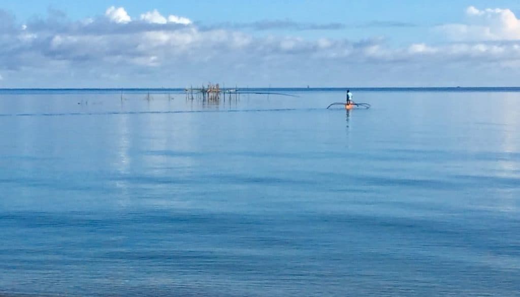 A man checks his bamboo fishing trap in Malay, Philippines, in an authentic travel shot.