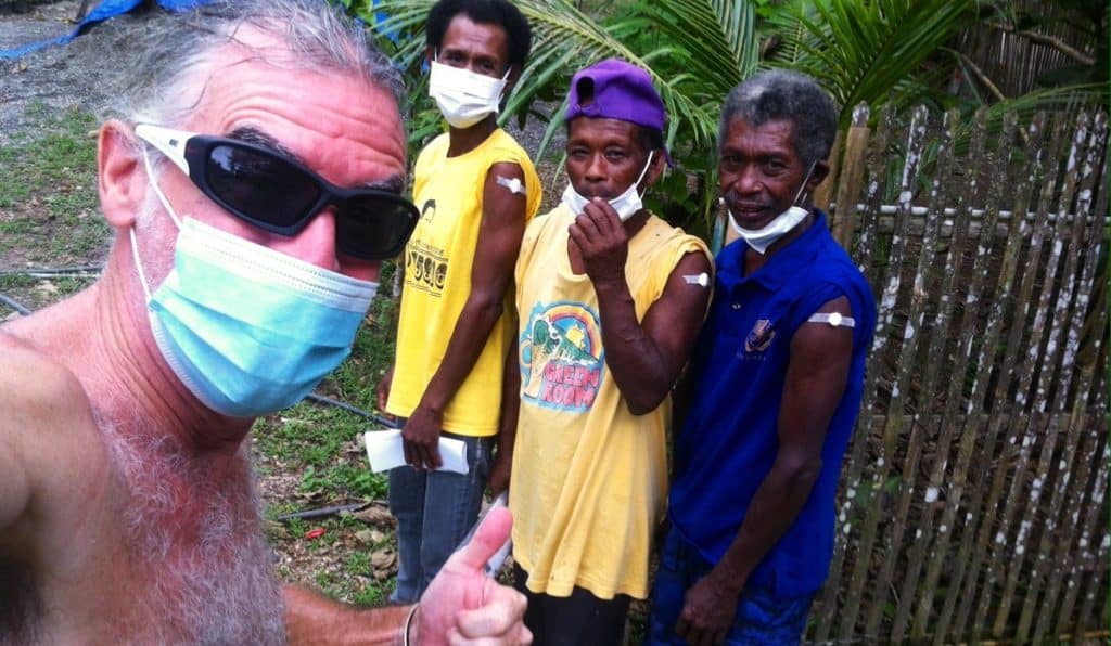 Theo and vaccinated Ati tribe members smile at the camera.