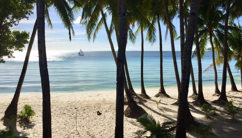A sailboat is seen through trees on Boracay Island in the Philippines.