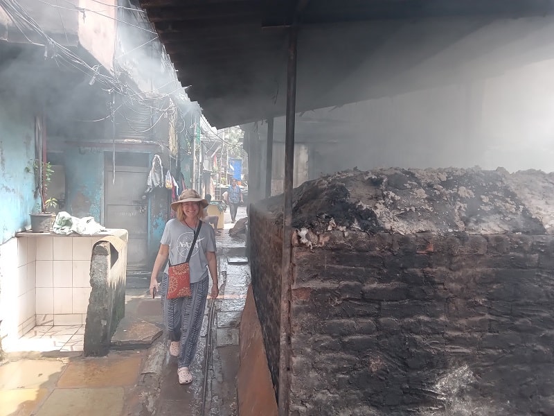 Ellen walks by the smoking clay pot oven in the residential section.