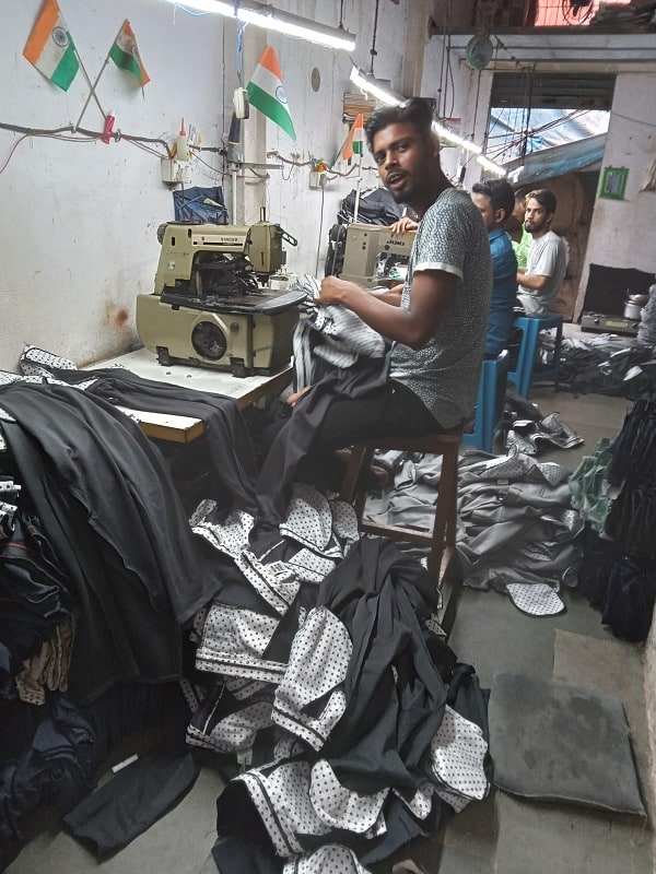 A man sews plastic sheeting together in Dharavi slum.